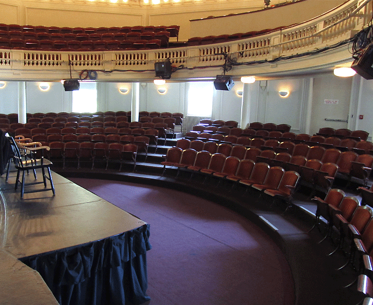 downstairs view of the semicircular wooden orchestra and balcony in Agassiz Theatre