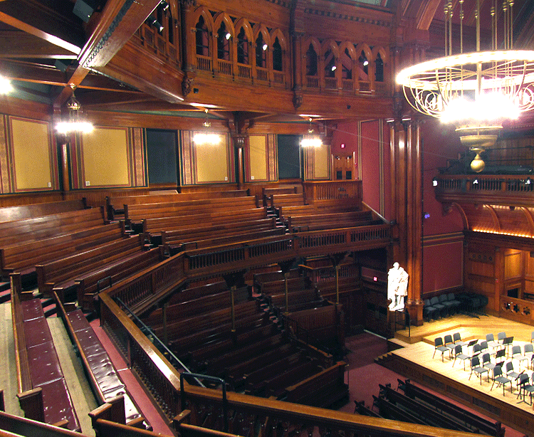 upstairs view of the semicircular wooden balcony, orchestra and stage in Sanders Theatre